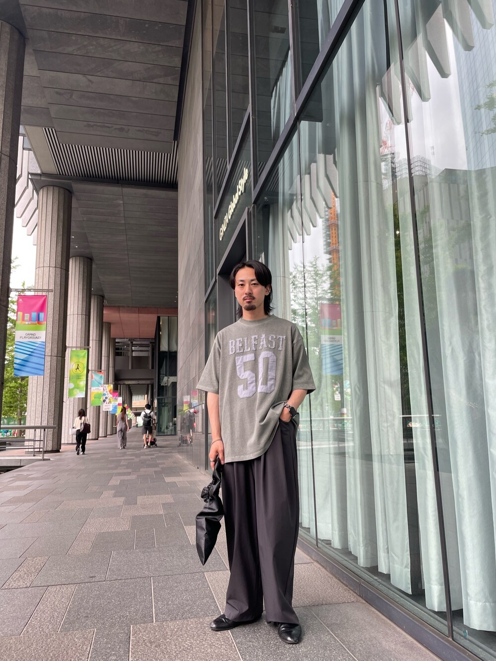 ブラック系のハンドバッグ、グリーン系のTシャツ/カットソー、グレー系のその他パンツを着用したメンズの夏コーディネートの1枚目の写真