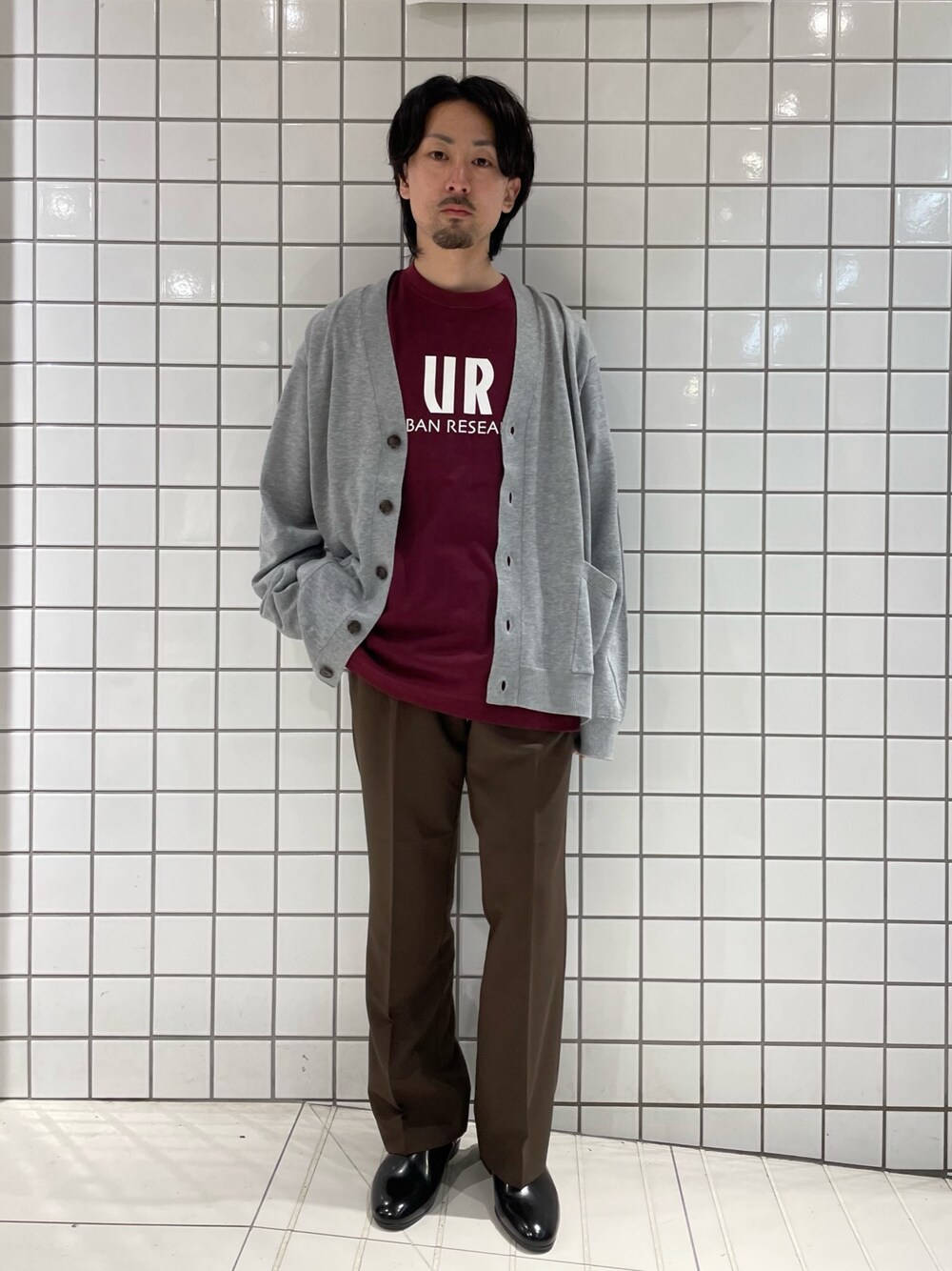 ブラウン系のスラックス、ブラック系のTシャツ/カットソー、グレー系のカーディガン/ボレロを着用したメンズの春コーディネートの1枚目の写真
