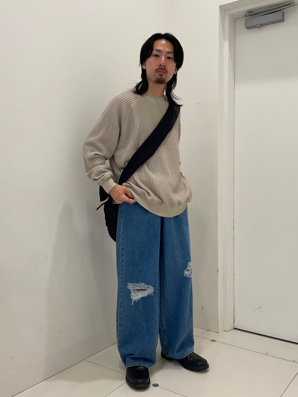 ベージュ系のスウェット、ブルー系のデニムパンツを着用したメンズの秋コーディネートの1枚目の写真