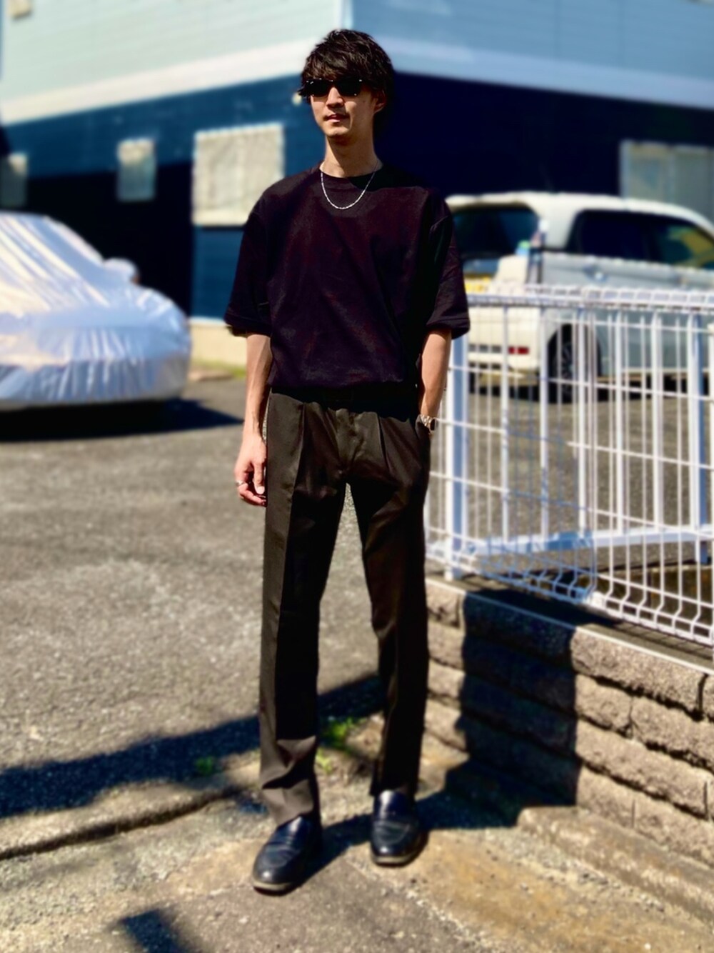 ブラック系のTシャツ/カットソー、ブラウン系のスラックス、ブラック系のローファーを着用したメンズの夏コーディネートの1枚目の写真