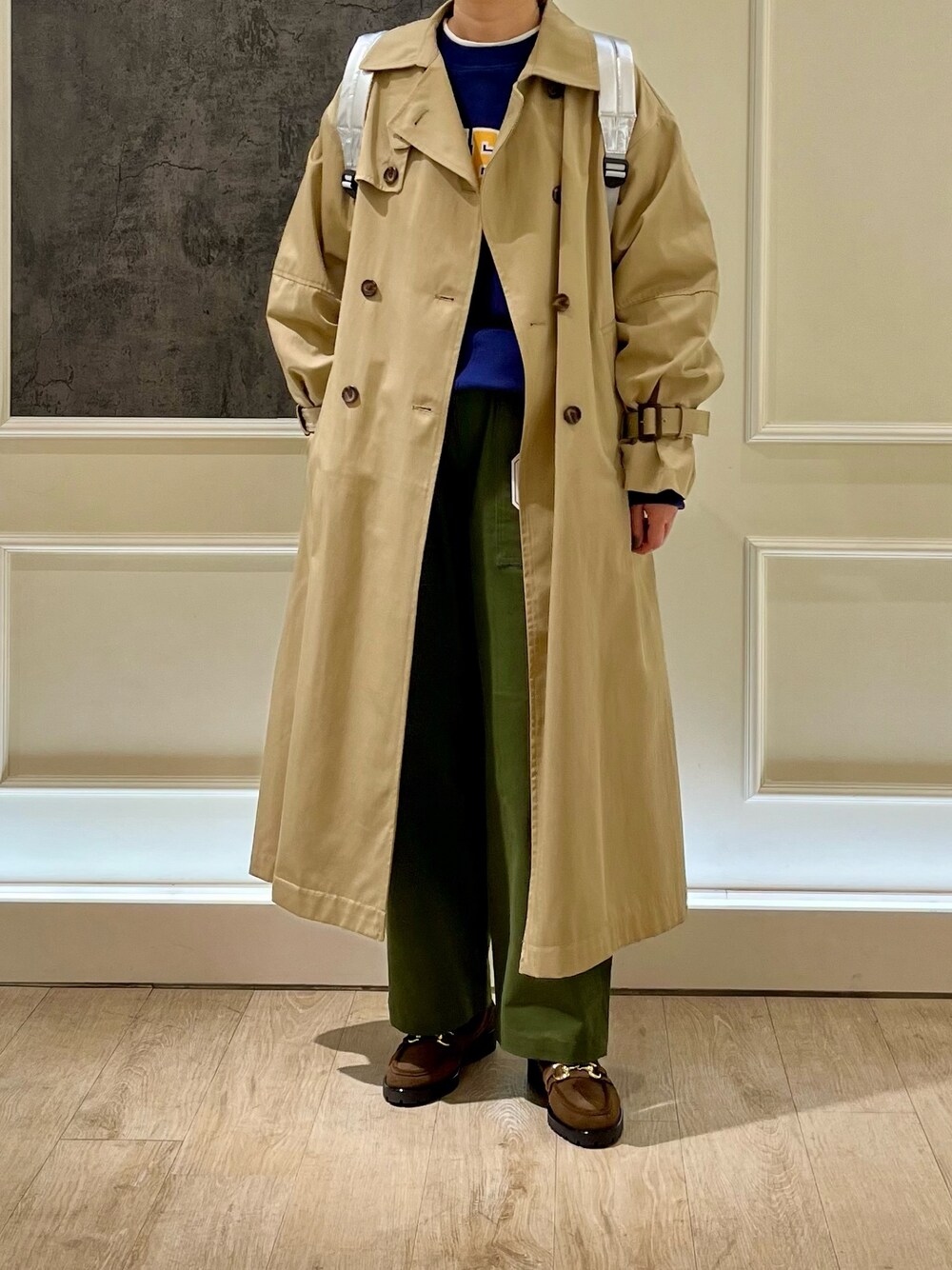 ベージュ系のトレンチコート、ブルー系のスウェット、シルバー系のバックパック/リュックを着用したレディースの冬コーディネートの1枚目の写真