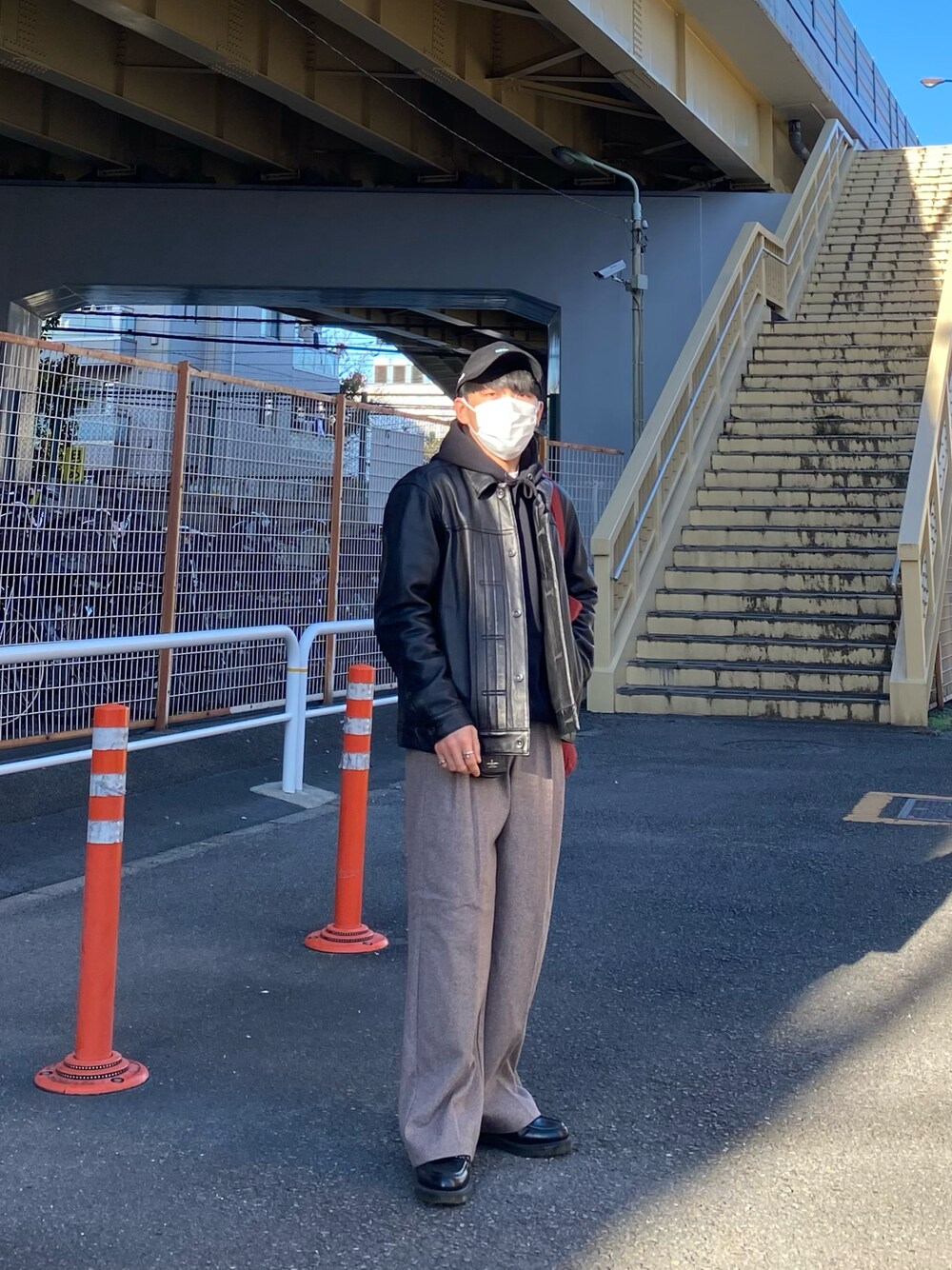 ブラック系のライダースジャケット、ブラック系のパーカー、レッド系のトートバッグを着用したメンズの秋コーディネートの1枚目の写真