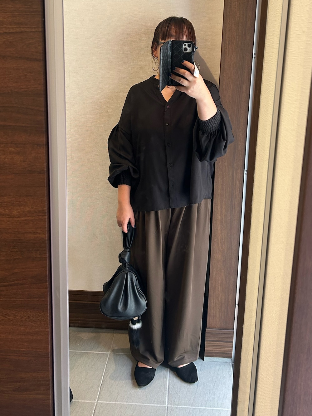 ブラック系のシャツ/ブラウス、ブラウン系のパンツ、ブラック系のハンドバッグを着用したレディースの秋コーディネートの1枚目の写真