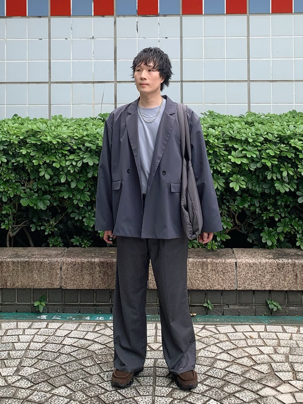 グレー系のトートバッグ、グレー系のテーラードジャケット、ブルー系のTシャツ/カットソーを着用したメンズの秋コーディネートの1枚目の写真