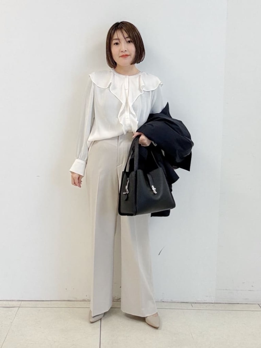 ベージュ系のその他パンツ、ブラック系のハンドバッグ、ホワイト系のシャツ/ブラウスを着用したレディースの冬コーディネートの1枚目の写真