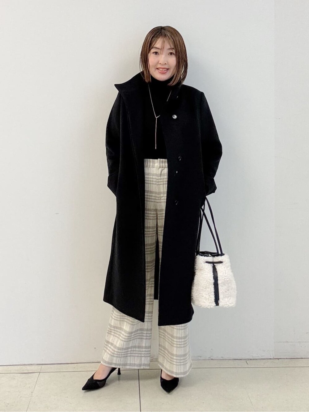 ブラック系のニット/セーター、グレー系のその他パンツ、ホワイト系のショルダーバッグを着用したレディースの冬コーディネートの1枚目の写真