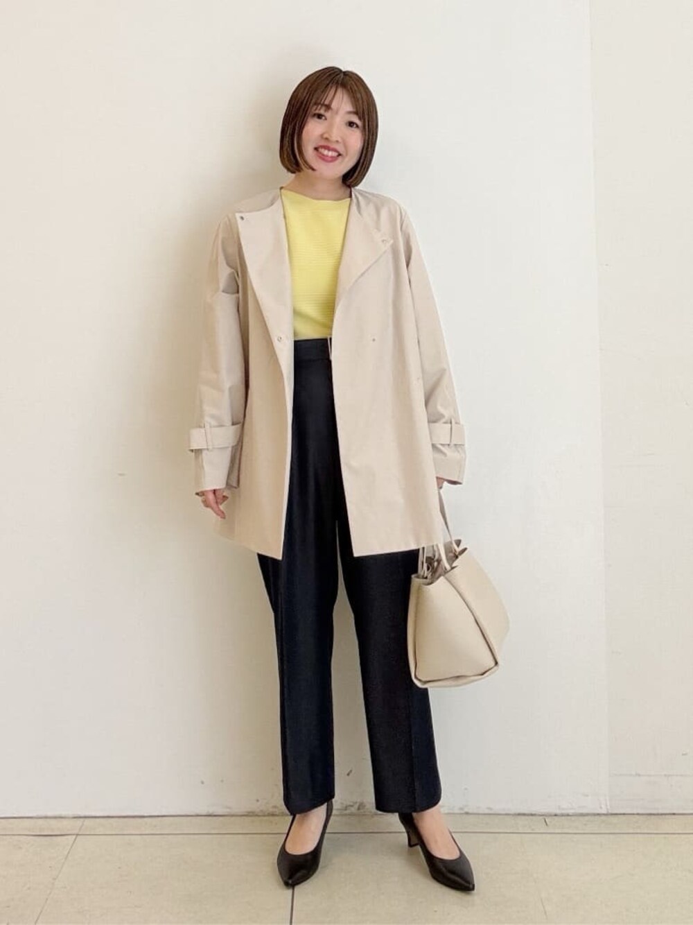 ブラック系のパンプス、ブルー系のその他パンツ、ベージュ系のトレンチコートを着用したレディースの春コーディネートの1枚目の写真