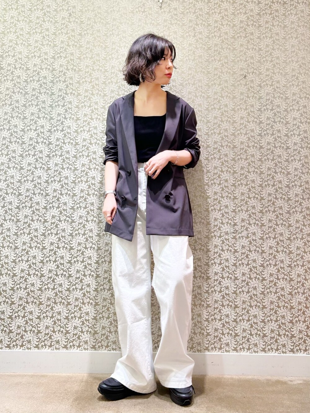 グレー系のテーラードジャケット、ブラック系のタンクトップ、ホワイト系のデニムパンツを着用したレディースの春コーディネートの1枚目の写真