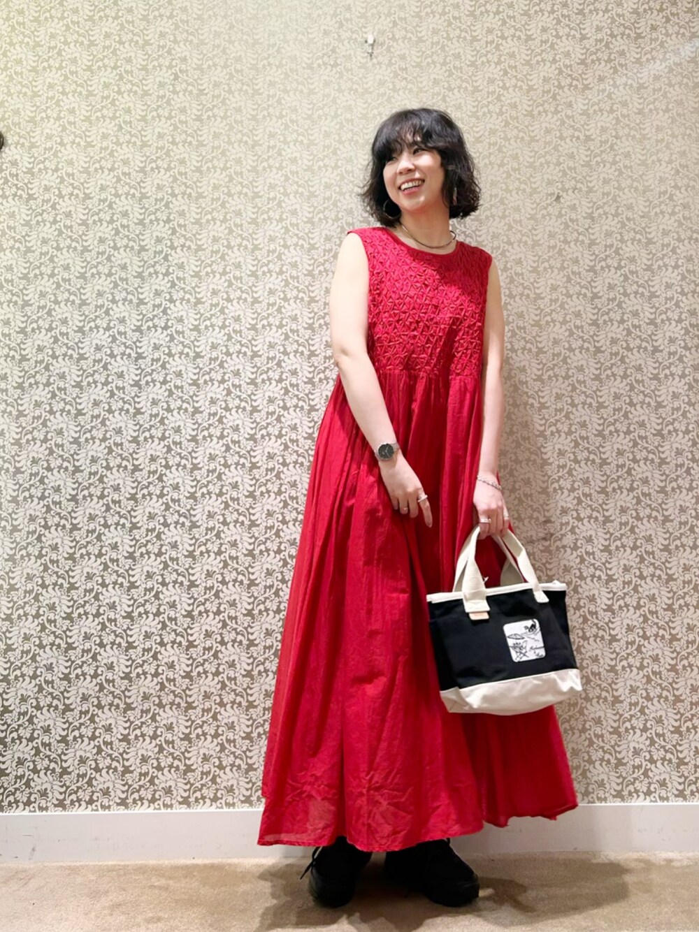 レッド系のワンピース、ブラック系のトートバッグを着用したレディースの春コーディネートの1枚目の写真