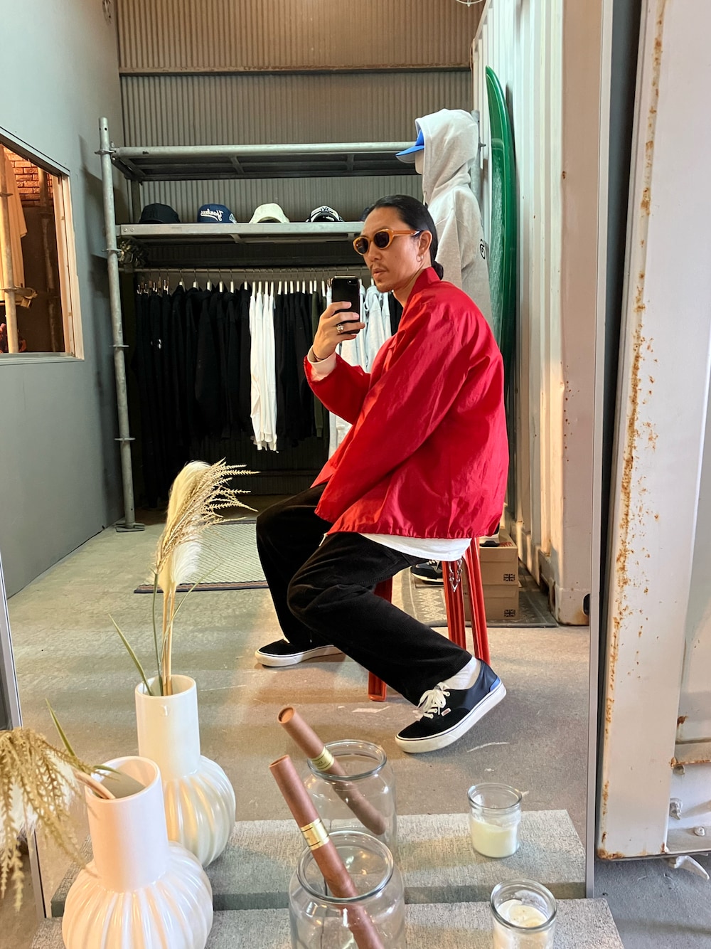 レッド系のナイロンジャケット、ブラウン系のその他パンツ、ブラック系のスニーカーを着用したメンズの秋コーディネートの1枚目の写真