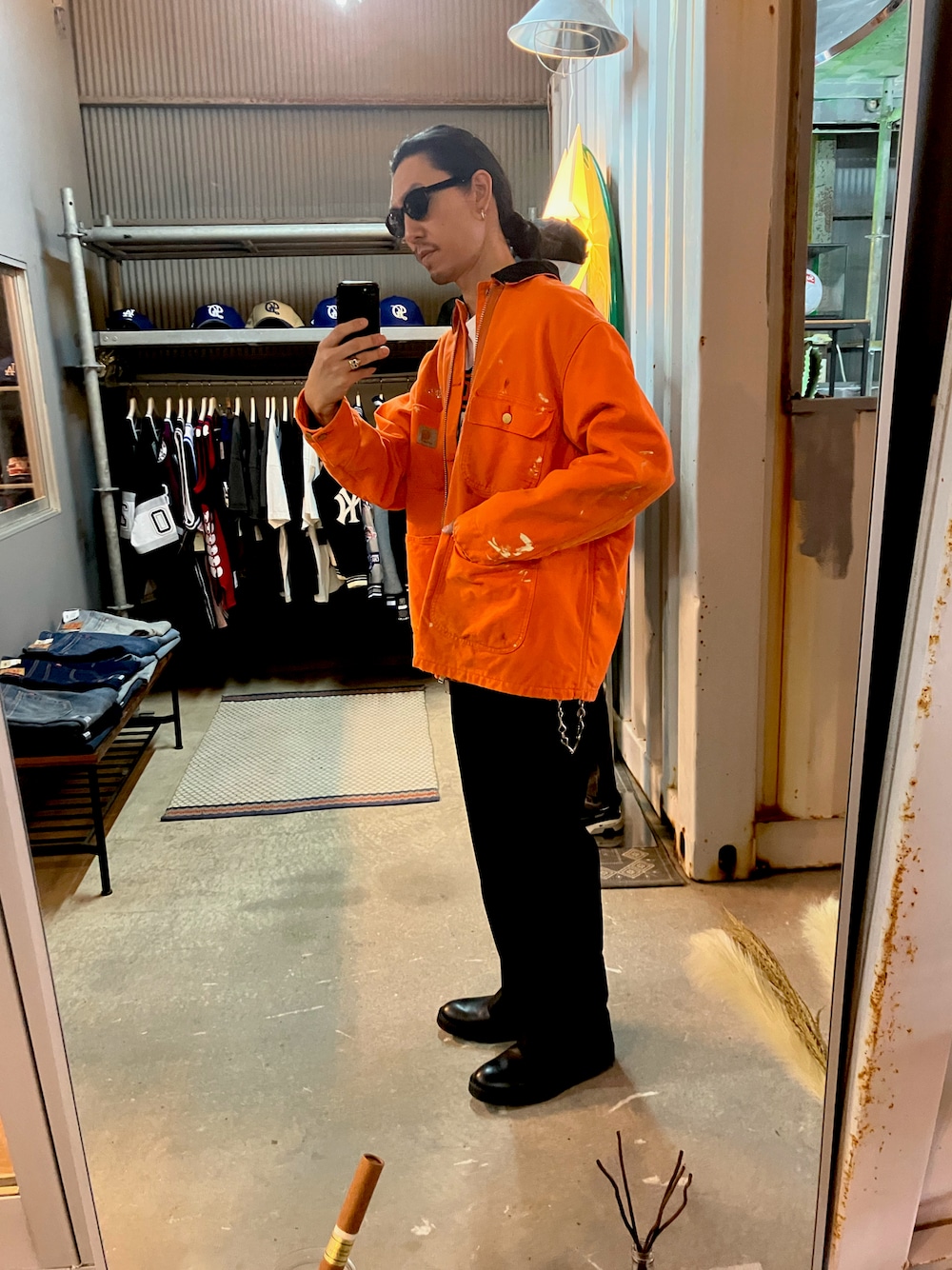 オレンジ系のカバーオール、ブラック系のスラックス、ブラック系のブーツを着用したメンズの冬コーディネートの1枚目の写真