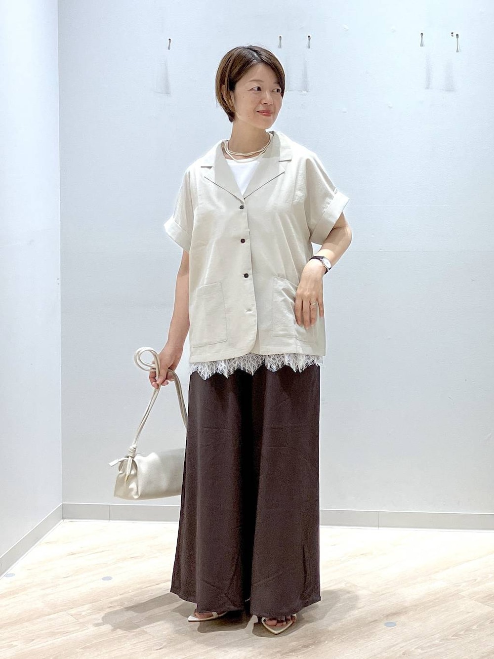 ベージュ系のショルダーバッグ、ブラウン系のその他パンツ、ベージュ系のシャツ/ブラウスを着用したレディースの夏コーディネートの1枚目の写真