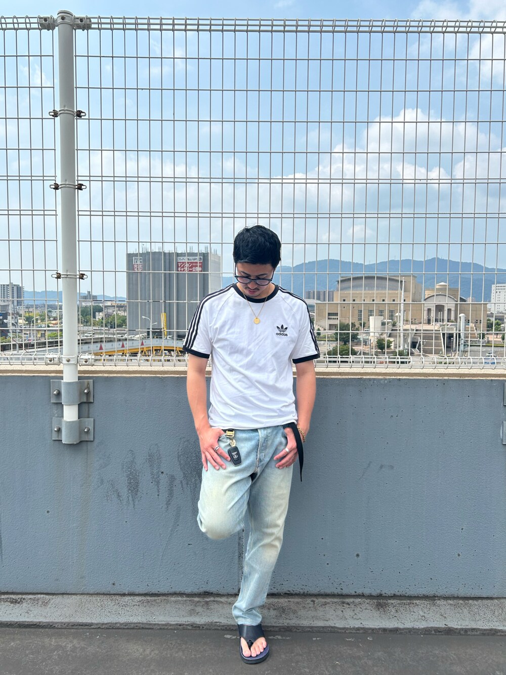 ブルー系のデニムパンツ、ホワイト系のTシャツ/カットソー、ブラック系のサンダルを着用したメンズの夏コーディネートの1枚目の写真