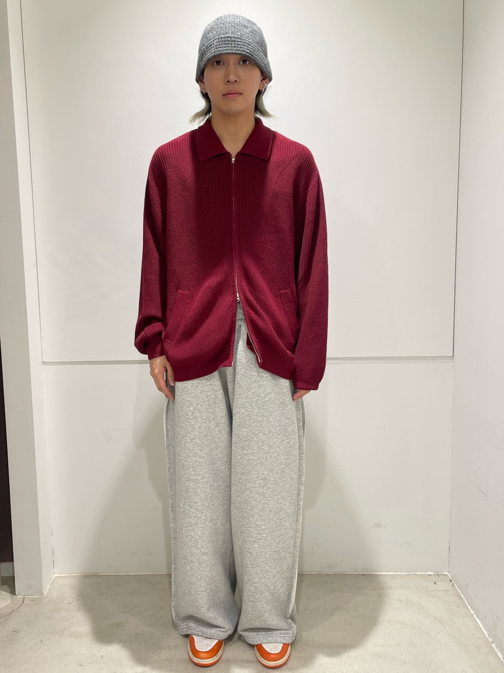 レッド系のニット/セーター、グレー系のパンツを着用したメンズの秋コーディネートの1枚目の写真