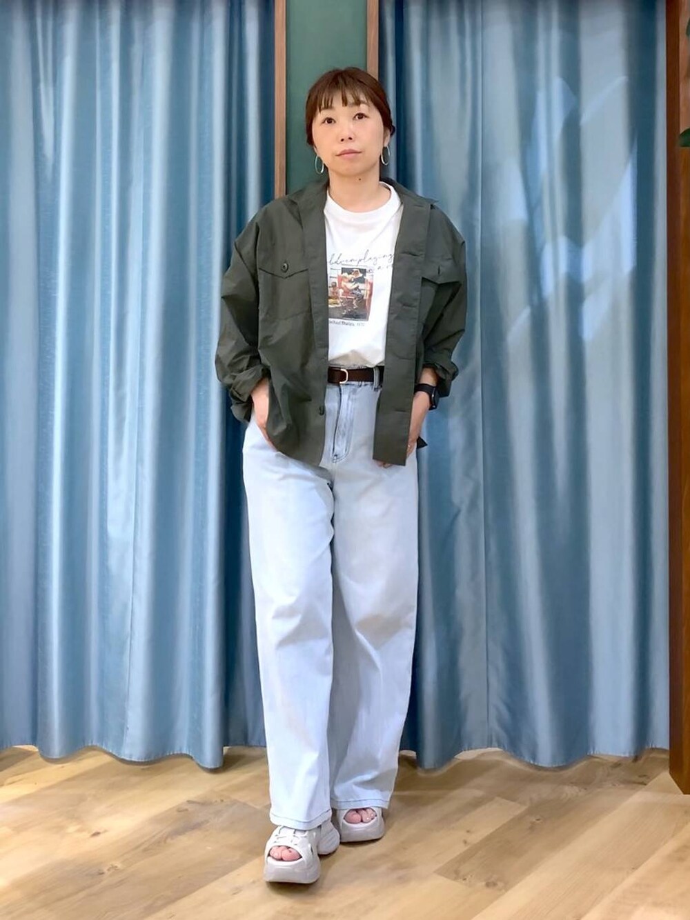 ブルー系のデニムパンツ、ホワイト系のTシャツ/カットソー、グレー系のサンダルを着用したレディースの春コーディネートの1枚目の写真