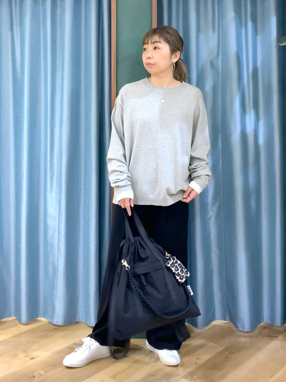 ブラック系のスラックス、ホワイト系のTシャツ/カットソー、グレー系のニット/セーターを着用したレディースの冬コーディネートの1枚目の写真