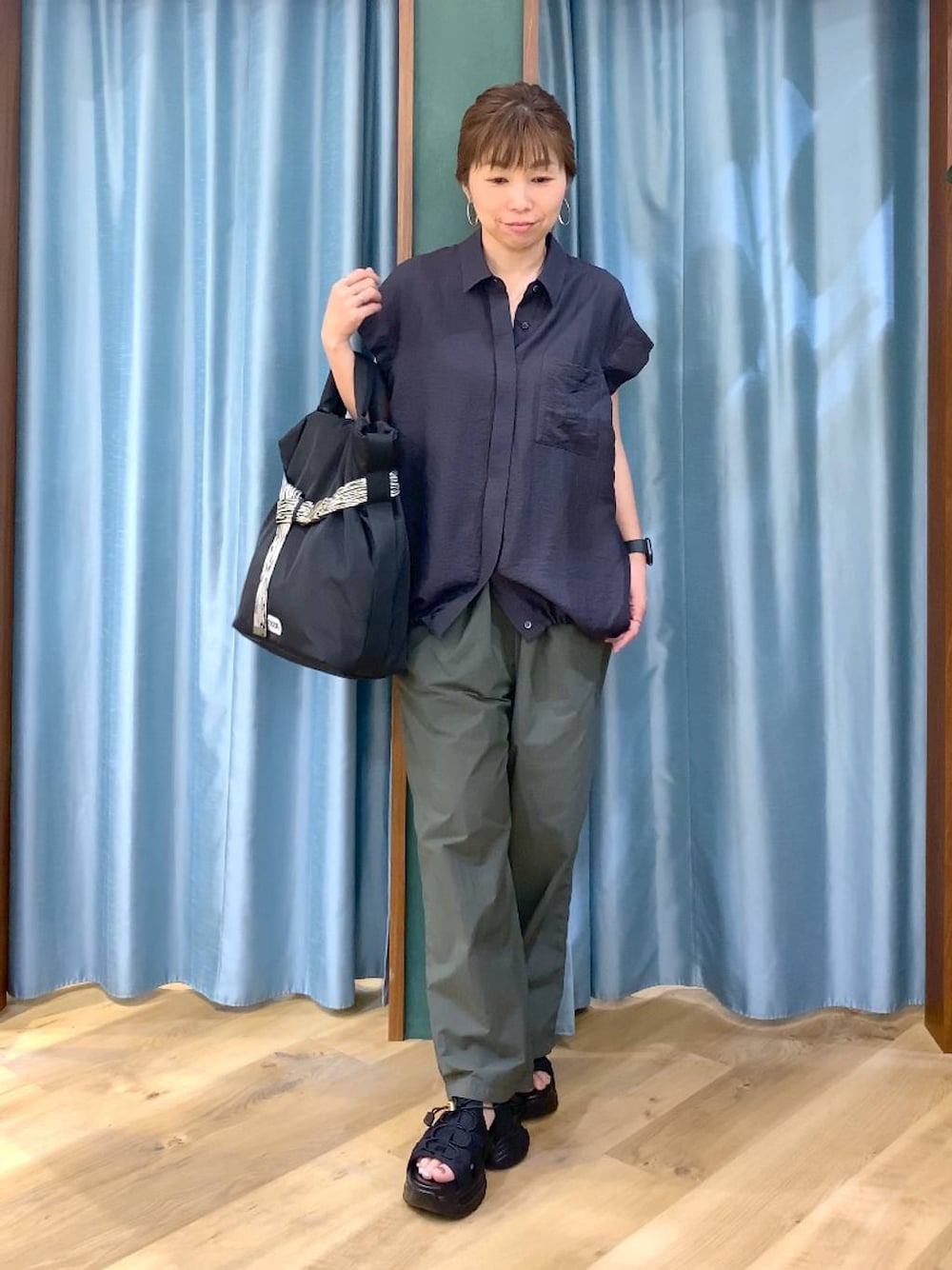 グリーン系のその他パンツ、ブラック系のトートバッグ、グレー系のシャツ/ブラウスを着用したレディースの春コーディネートの1枚目の写真