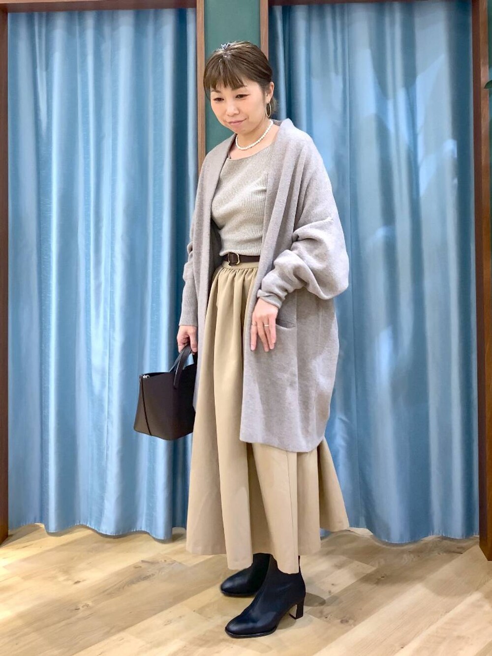 ブラック系のブーツ、ベージュ系のニット/セーター、ブラウン系のショルダーバッグを着用したレディースの秋コーディネートの1枚目の写真