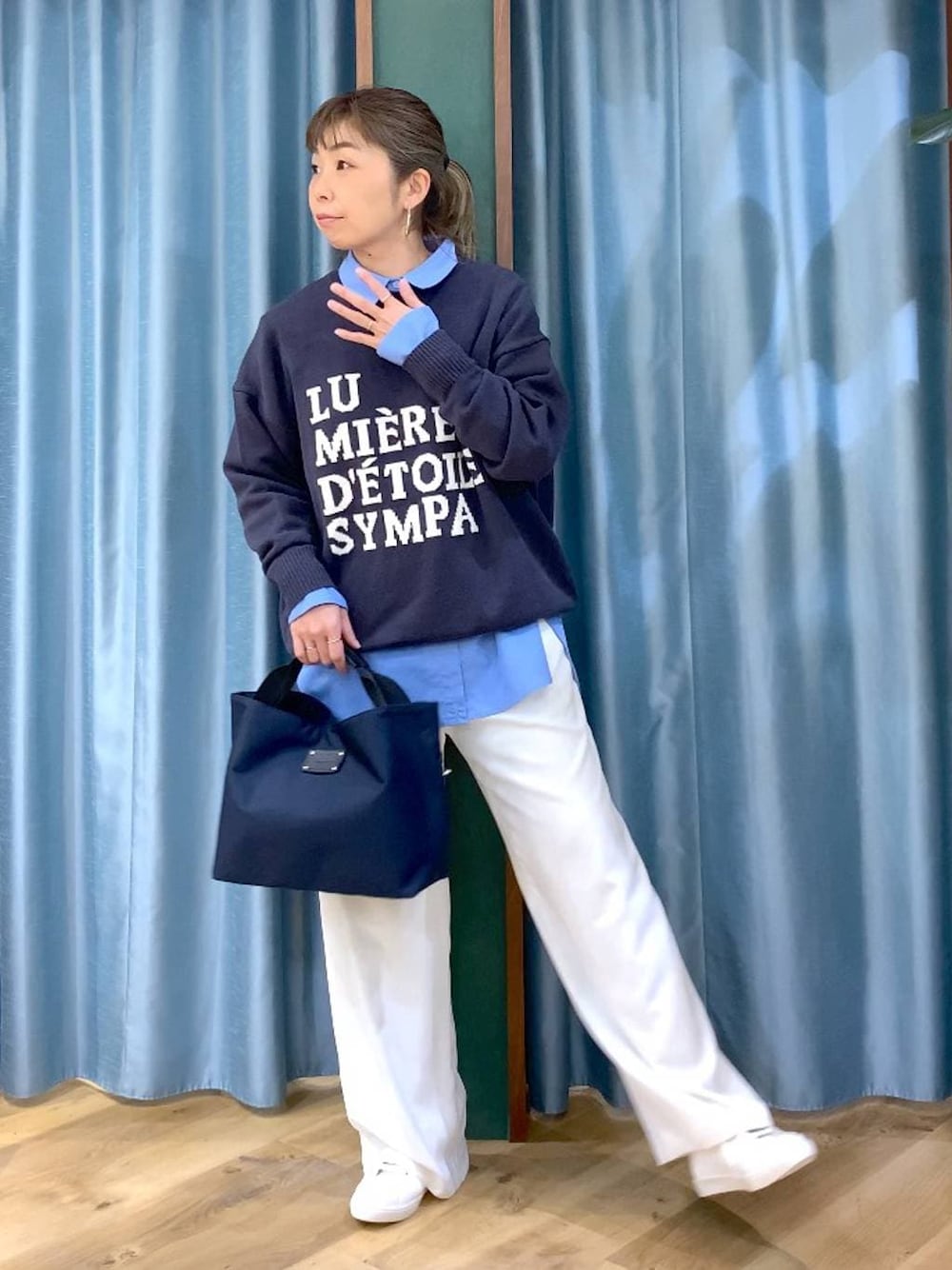 ホワイト系のスラックス、ブルー系のトートバッグ、グレー系のニット/セーターを着用したレディースの冬コーディネートの1枚目の写真