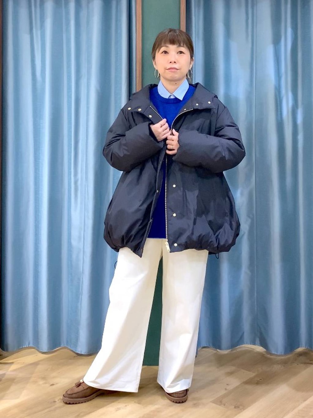 ブルー系のシャツ/ブラウス、ブラック系のダウンジャケット/コート、ブラウン系のローファーを着用したレディースの秋コーディネートの1枚目の写真