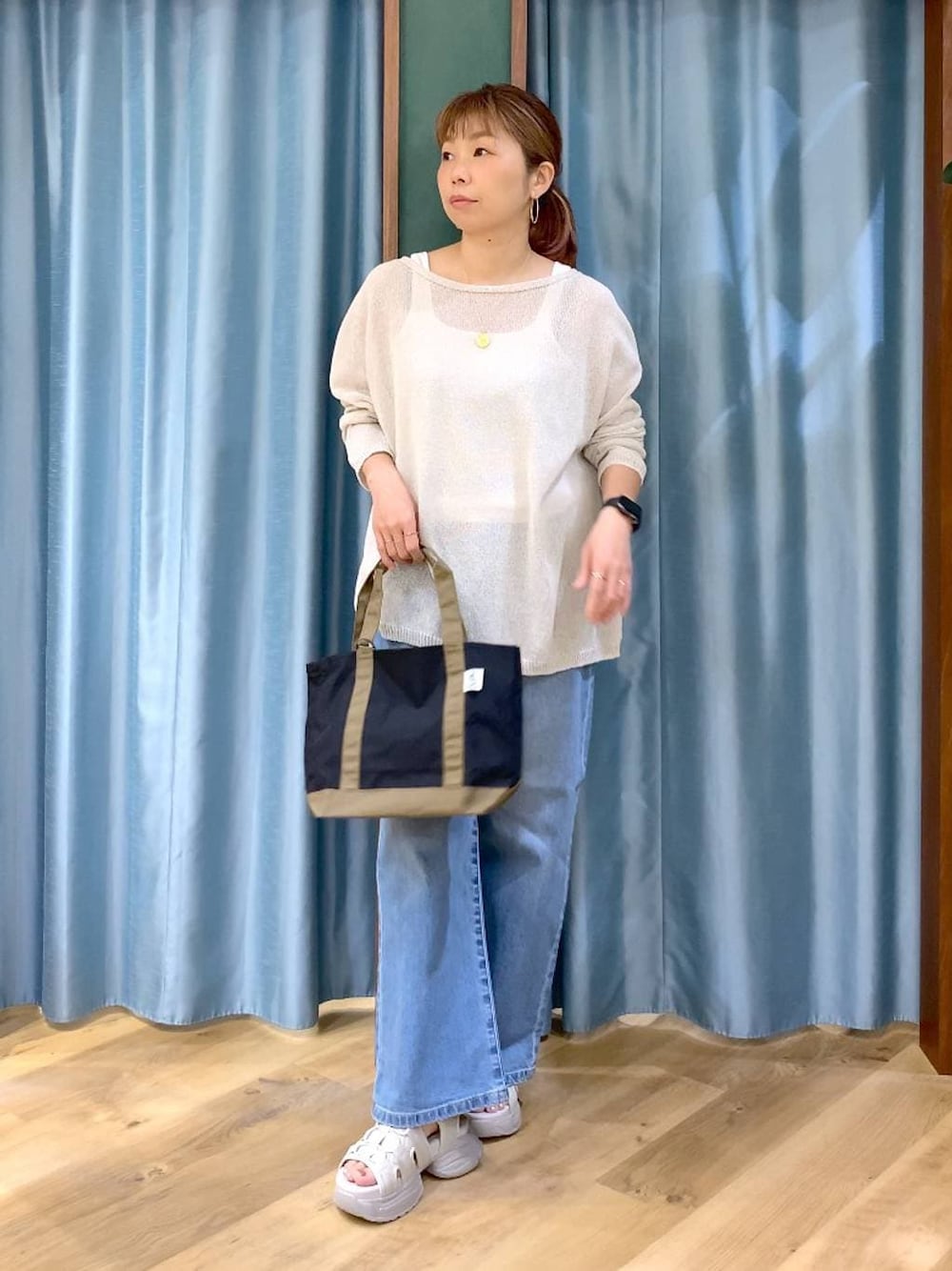 ブルー系のデニムパンツ、ホワイト系のタンクトップ、ホワイト系のニット/セーターを着用したレディースの春コーディネートの1枚目の写真