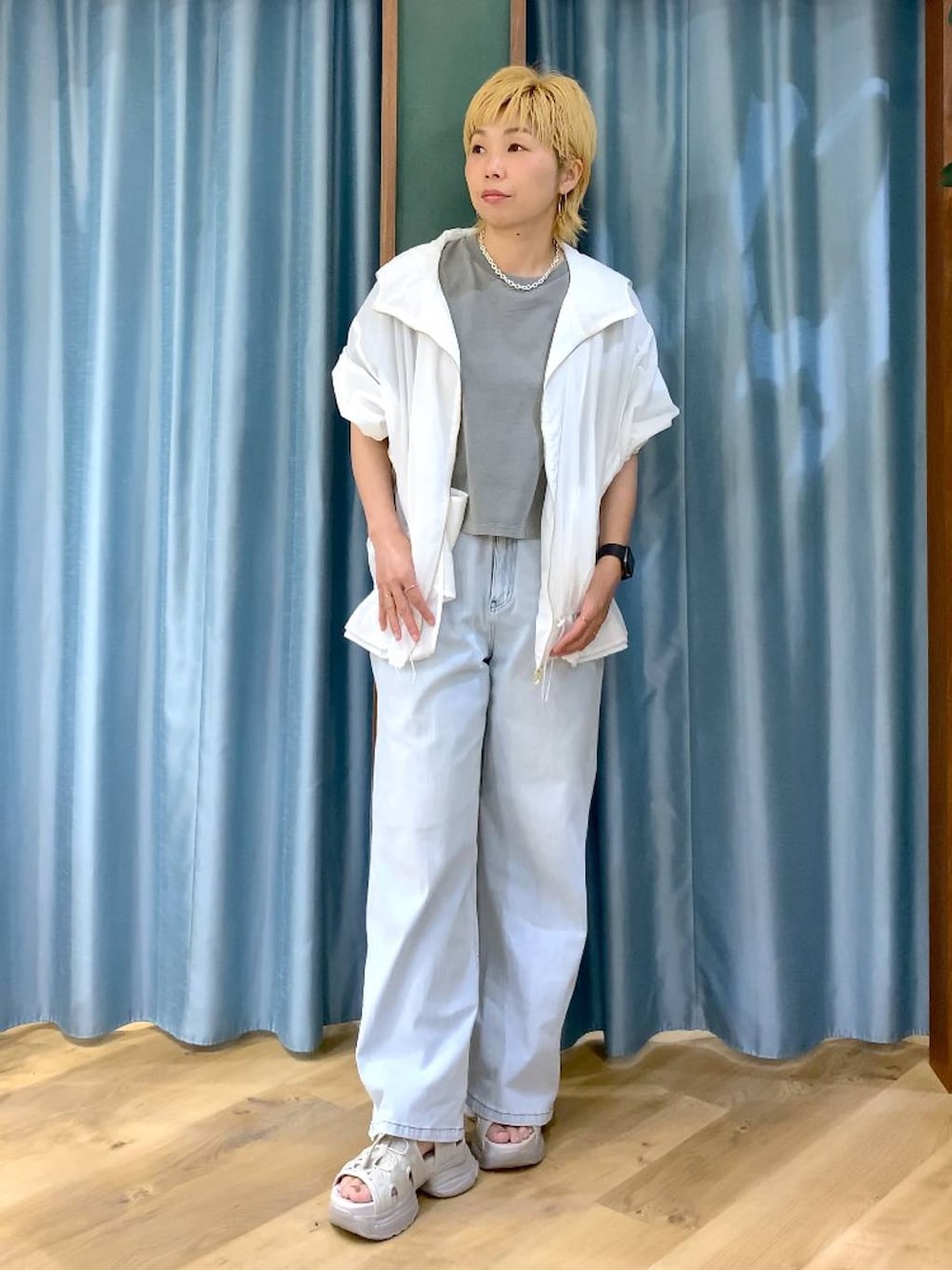 ブルー系のデニムパンツ、グレー系のサンダル、ホワイト系のブルゾンを着用したレディースの春コーディネートの1枚目の写真