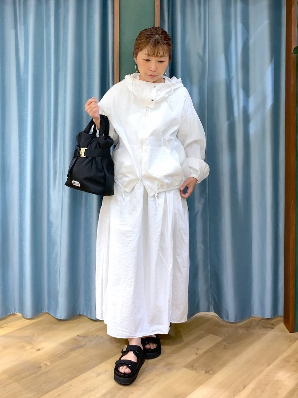 ホワイト系のスカート、ホワイト系のブルゾン、ブラック系のトートバッグを着用したレディースの春コーディネートの1枚目の写真