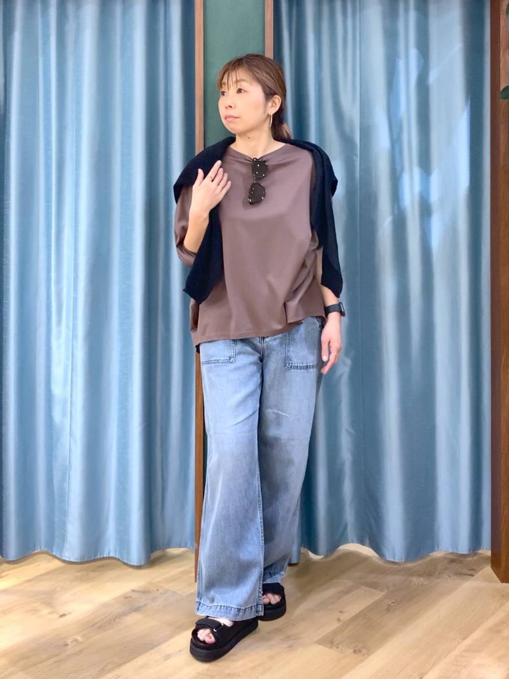 ブラウン系のTシャツ/カットソー、ブルー系のデニムパンツ、ブラック系のニット/セーターを着用したレディースの春コーディネートの1枚目の写真