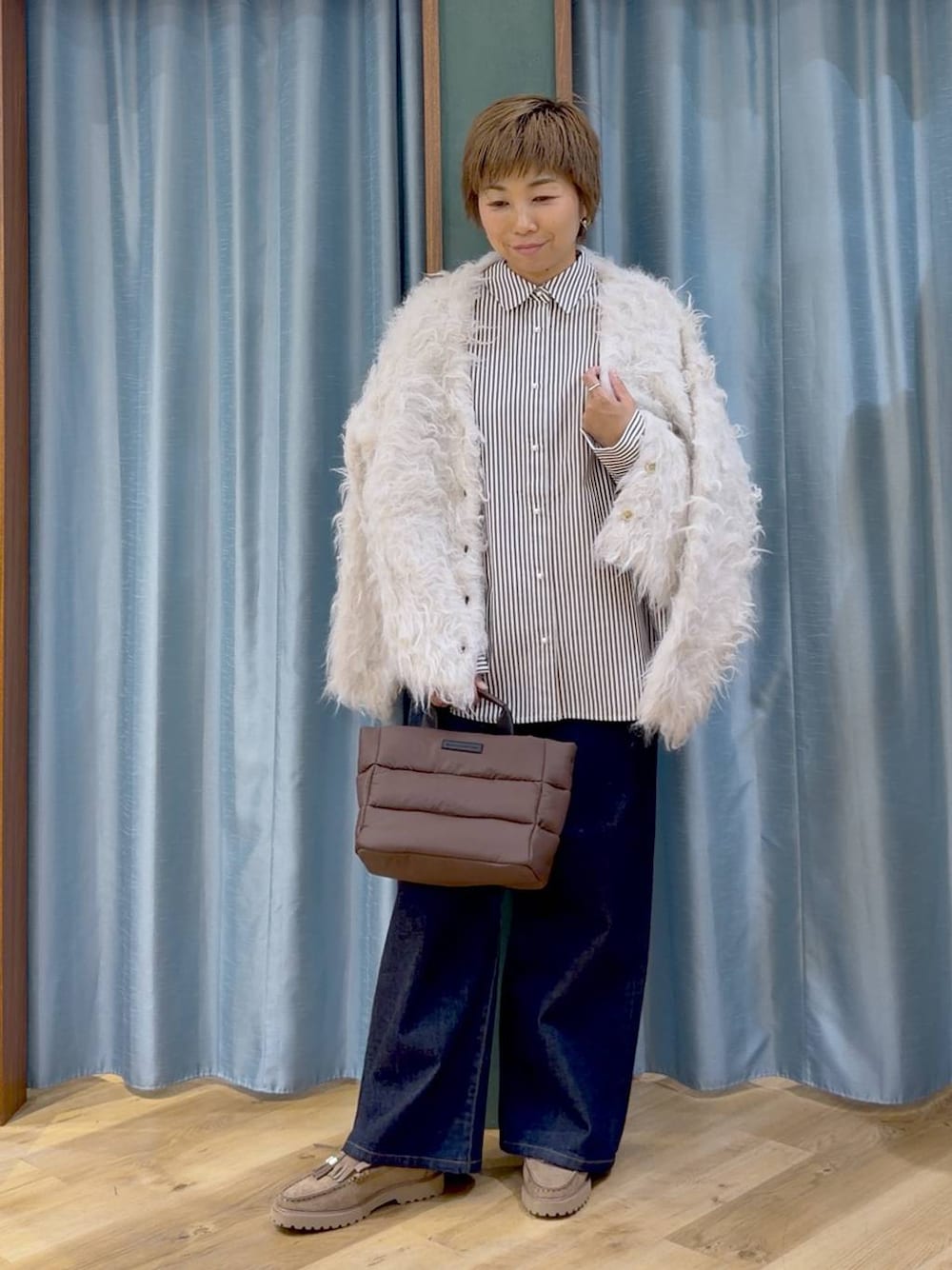 ベージュ系のシャツ/ブラウス、ブラウン系のトートバッグ、ブルー系のデニムパンツを着用したレディースの秋コーディネートの1枚目の写真