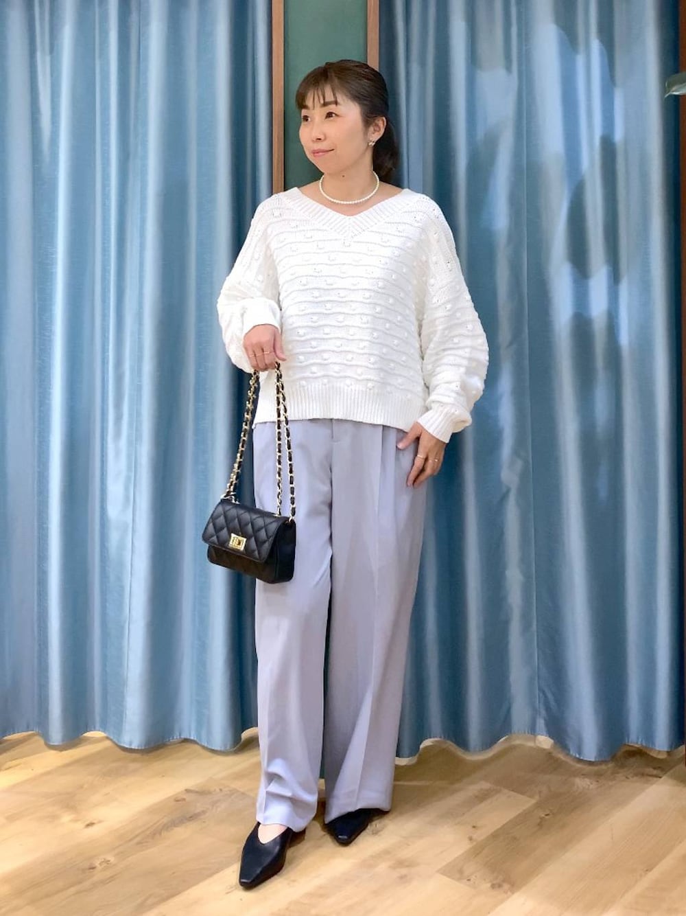 ホワイト系のニット/セーター、グレー系のその他パンツ、ブラック系のショルダーバッグを着用したレディースの冬コーディネートの1枚目の写真