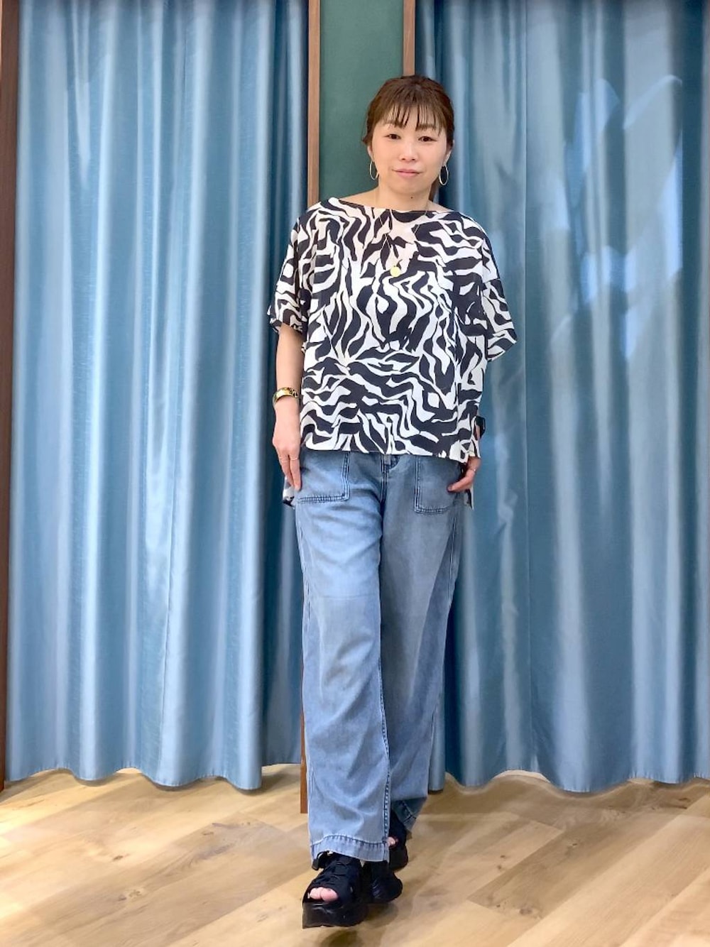 ブルー系のデニムパンツ、ブラック系のシャツ/ブラウス、ブラック系のサンダルを着用したレディースの春コーディネートの1枚目の写真