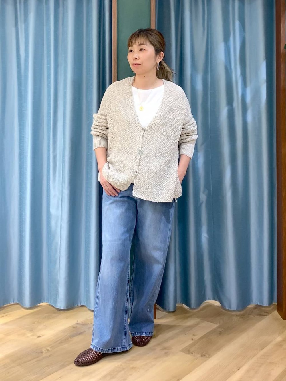 ブルー系のデニムパンツ、ホワイト系のTシャツ/カットソー、ベージュ系のカーディガン/ボレロを着用したレディースの春コーディネートの1枚目の写真