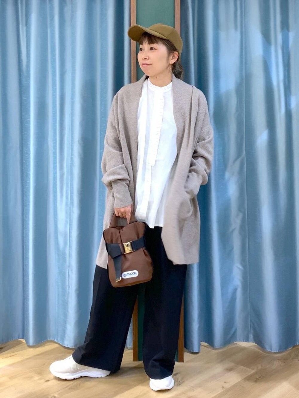 ホワイト系のシャツ/ブラウス、ベージュ系のカーディガン/ボレロ、ブラック系のスラックスを着用したレディースの秋コーディネートの1枚目の写真