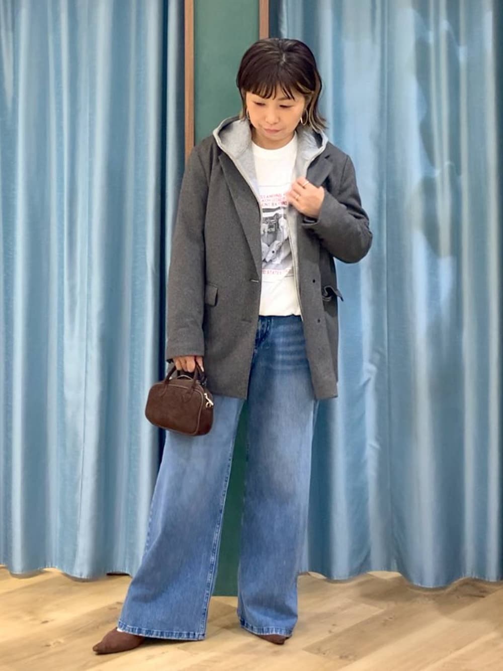 ブルー系のデニムパンツ、ブラウン系のテーラードジャケット、グレー系のパーカーを着用したレディースの秋コーディネートの1枚目の写真