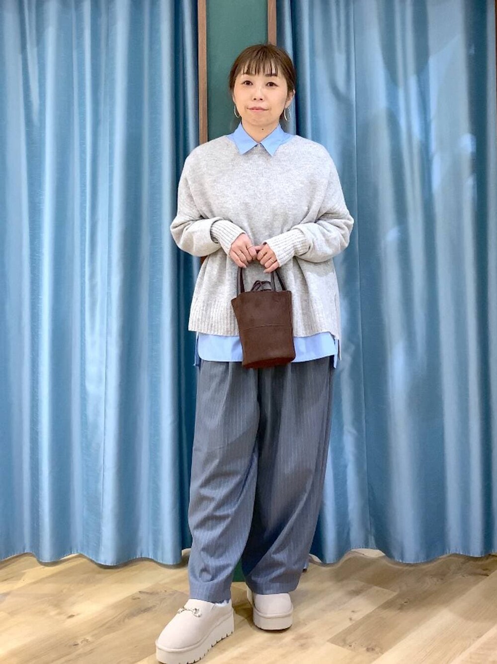 ブルー系のシャツ/ブラウス、ベージュ系のスリッポン、ベージュ系のニット/セーターを着用したレディースの冬コーディネートの1枚目の写真