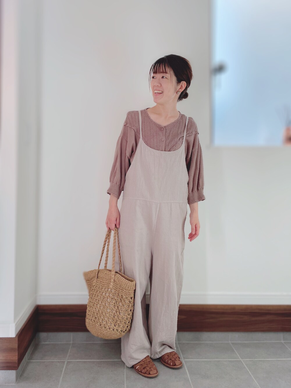 イエロー系のかごバッグ、ブラウン系のカーディガン/ボレロ、ベージュ系のサロペット/オーバーオールを着用したレディースの夏コーディネートの1枚目の写真