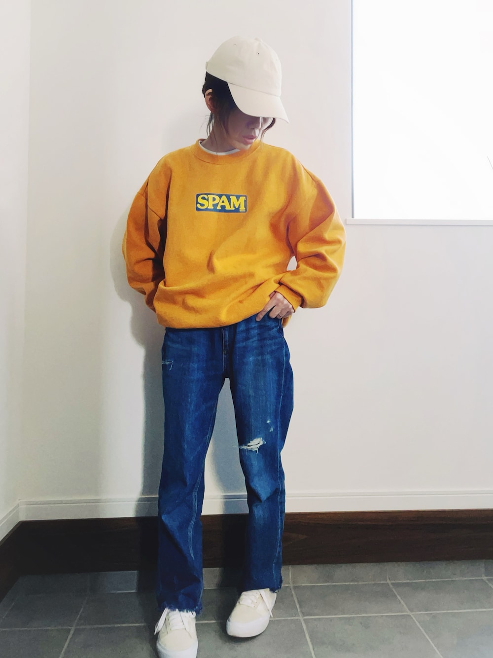 ブルー系のデニムパンツ、ホワイト系のスニーカー、イエロー系のスウェットを着用したレディースの冬コーディネートの1枚目の写真