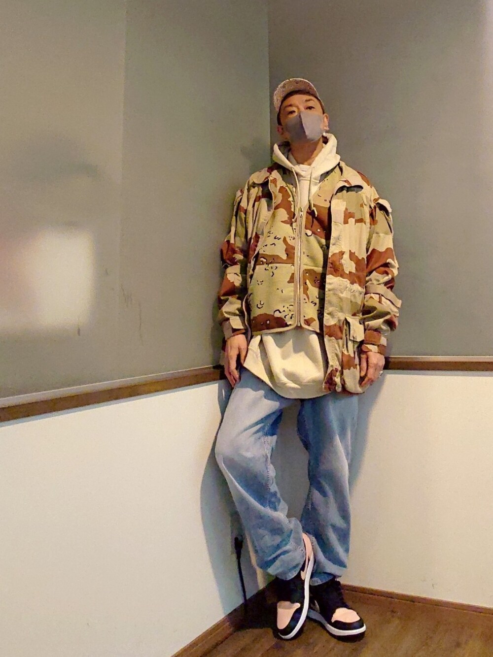 ベージュ系のミリタリージャケット、ブラウン系のベスト、ベージュ系のパーカーを着用したメンズの春コーディネートの2枚目の写真