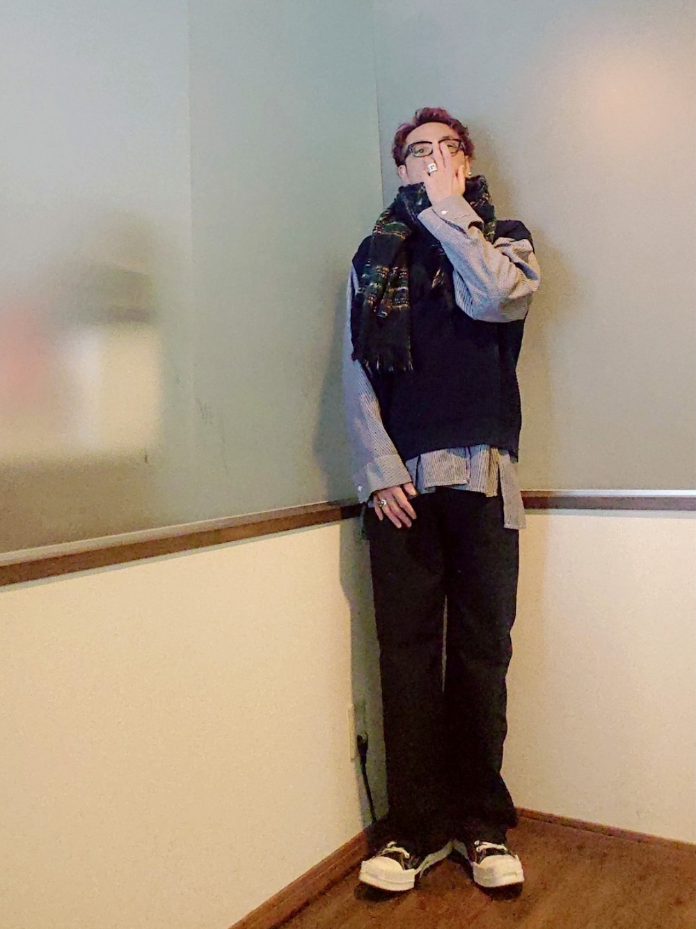 ベージュ系のチェスターコート、ブルー系のベスト、ブラック系のシャツ/ブラウスを着用したメンズの春コーディネートの2枚目の写真