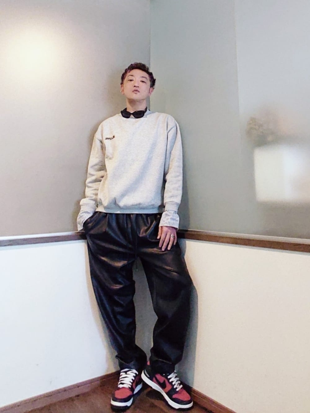 グレー系のスウェット、ブラック系のパンツ、レッド系のスニーカーを着用したメンズの秋コーディネートの1枚目の写真