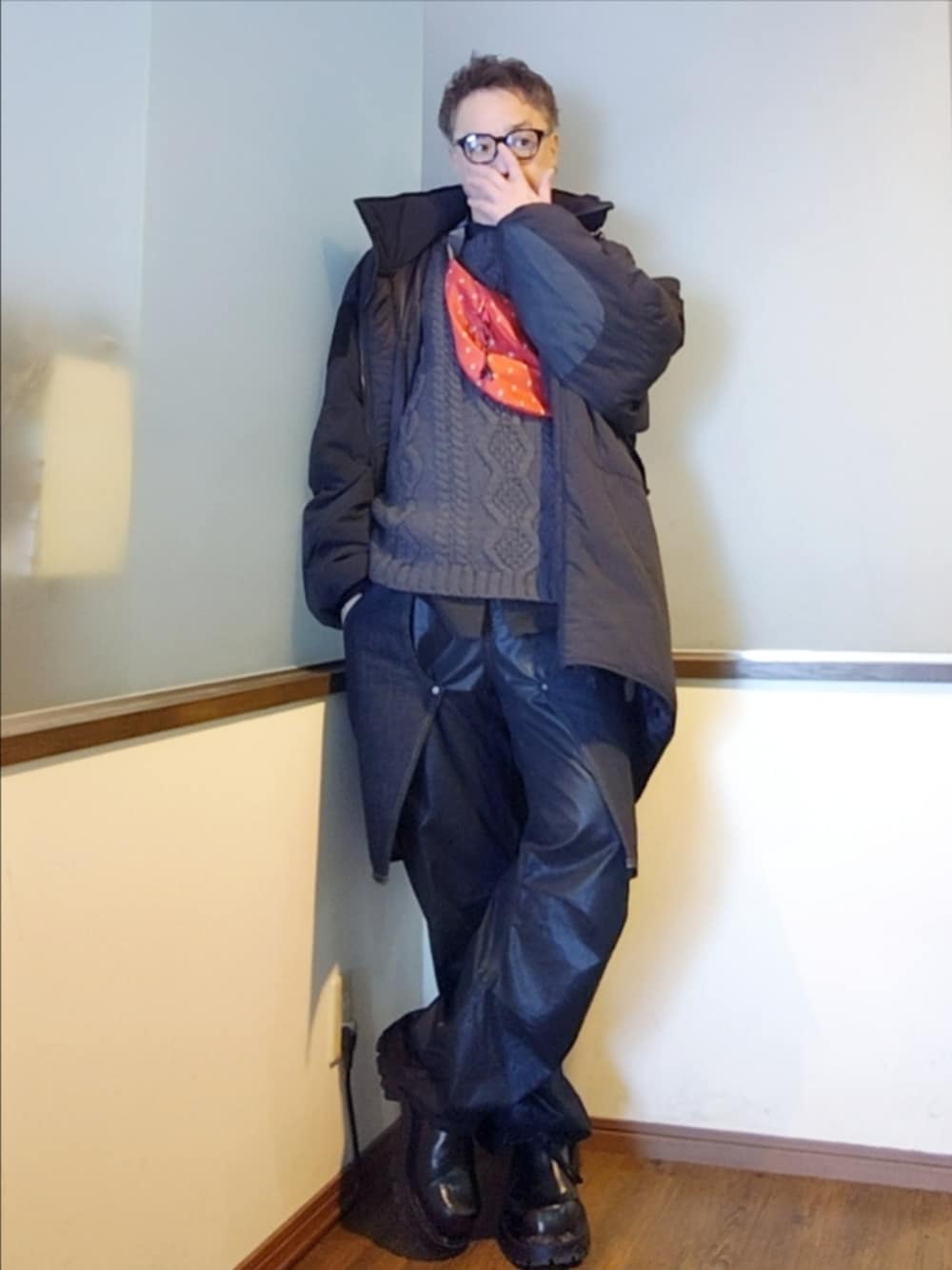 ブラック系のダウンジャケット/コート、レッド系のショルダーバッグ、グレー系のニット/セーターを着用したメンズの冬コーディネートの1枚目の写真