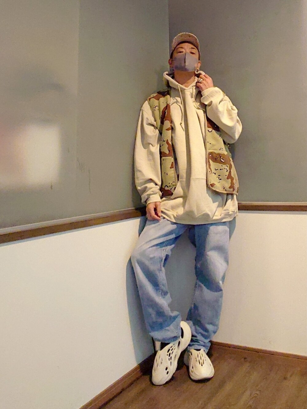 ベージュ系のミリタリージャケット、ブラウン系のベスト、ベージュ系のパーカーを着用したメンズの春コーディネートの3枚目の写真