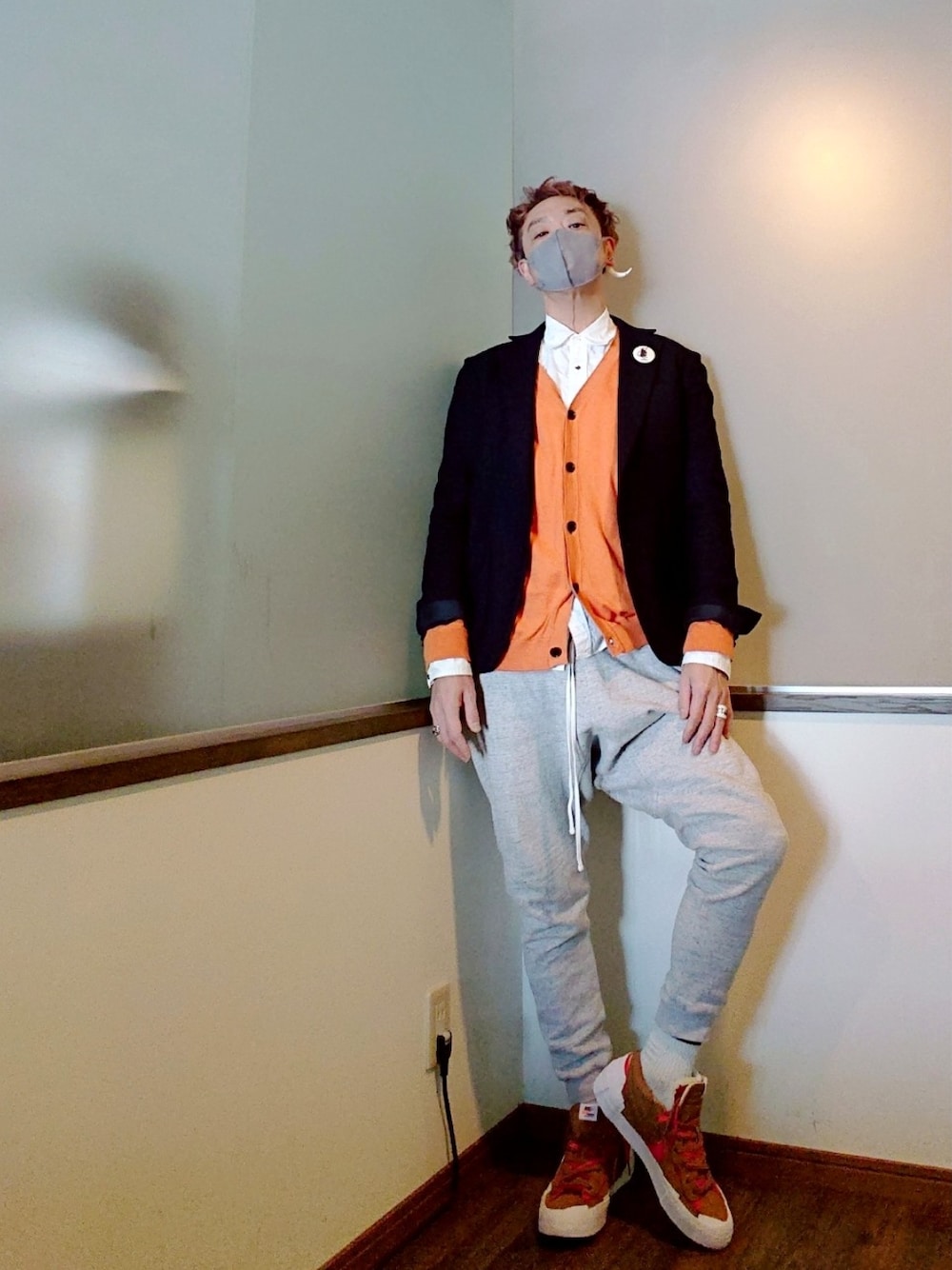 グリーン系のトレンチコート、オレンジ系のカーディガン/ボレロ、グレー系のスウェットパンツを着用したメンズの春コーディネートの2枚目の写真