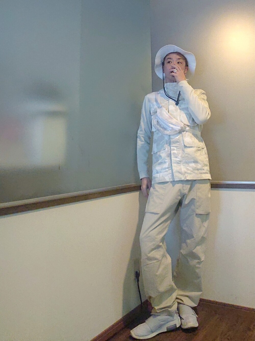 ブラック系のポンチョ、ベージュ系のチノパンツ、グレー系のスニーカーを着用したメンズの春コーディネートの2枚目の写真