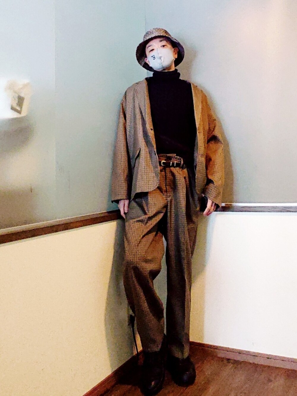 ブラック系のニット/セーター、ブラック系のブーツ、ブラック系のチェスターコートを着用したメンズの冬コーディネートの2枚目の写真