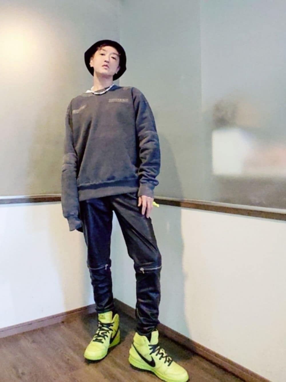 グレー系のスウェット、ブラック系のパンツ、グリーン系のスニーカーを着用したメンズの秋コーディネートの1枚目の写真