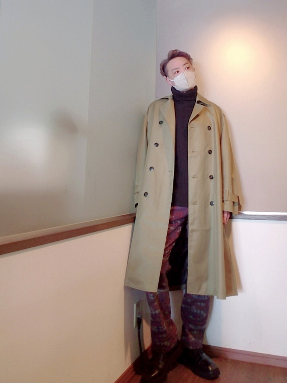 グリーン系のトレンチコート、レッド系のパンツ、ブラック系のドレスシューズを着用したメンズの冬コーディネートの1枚目の写真