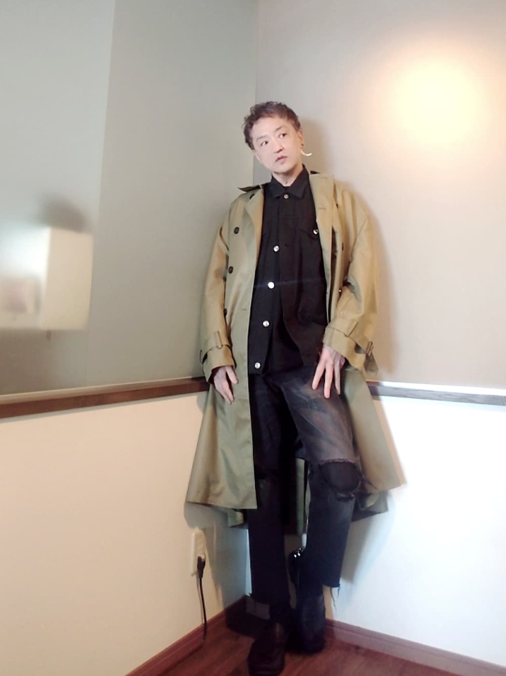 グリーン系のトレンチコート、ブラック系のシャツ/ブラウス、ブラック系のデニムパンツを着用したメンズの春コーディネートの1枚目の写真