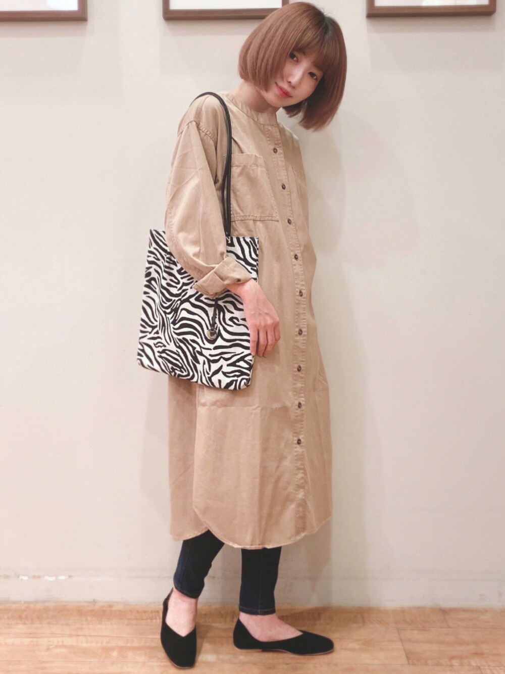 ブルー系のデニムパンツ、ブラック系のパンプス、ベージュ系のシャツワンピースを着用したレディースの秋コーディネートの1枚目の写真