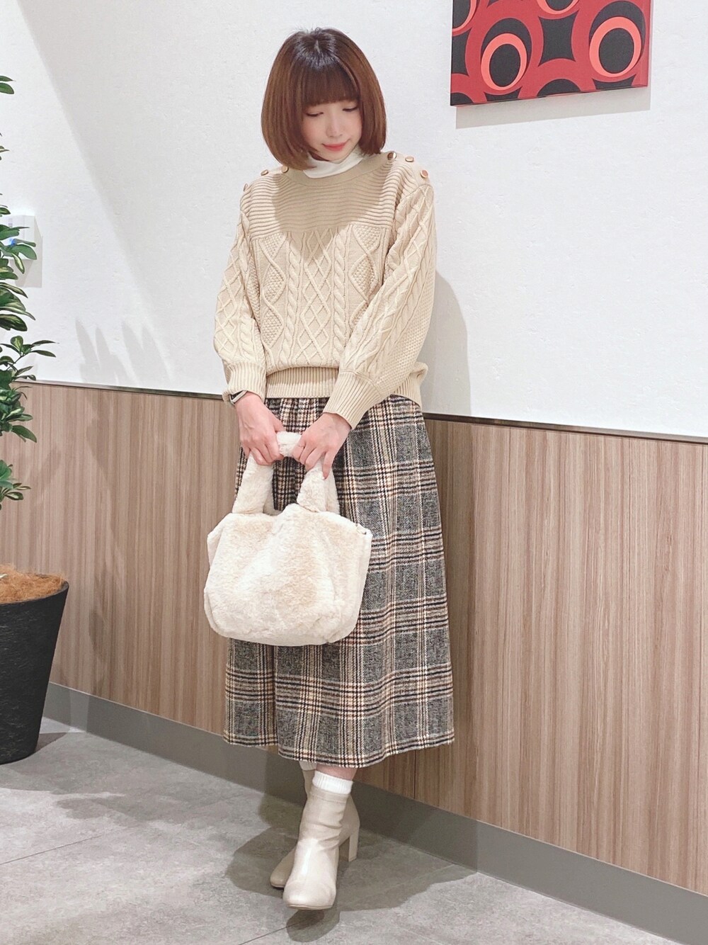 ベージュ系のニット/セーター、ホワイト系のTシャツ/カットソー、イエロー系のスカートを着用したレディースの冬コーディネートの1枚目の写真